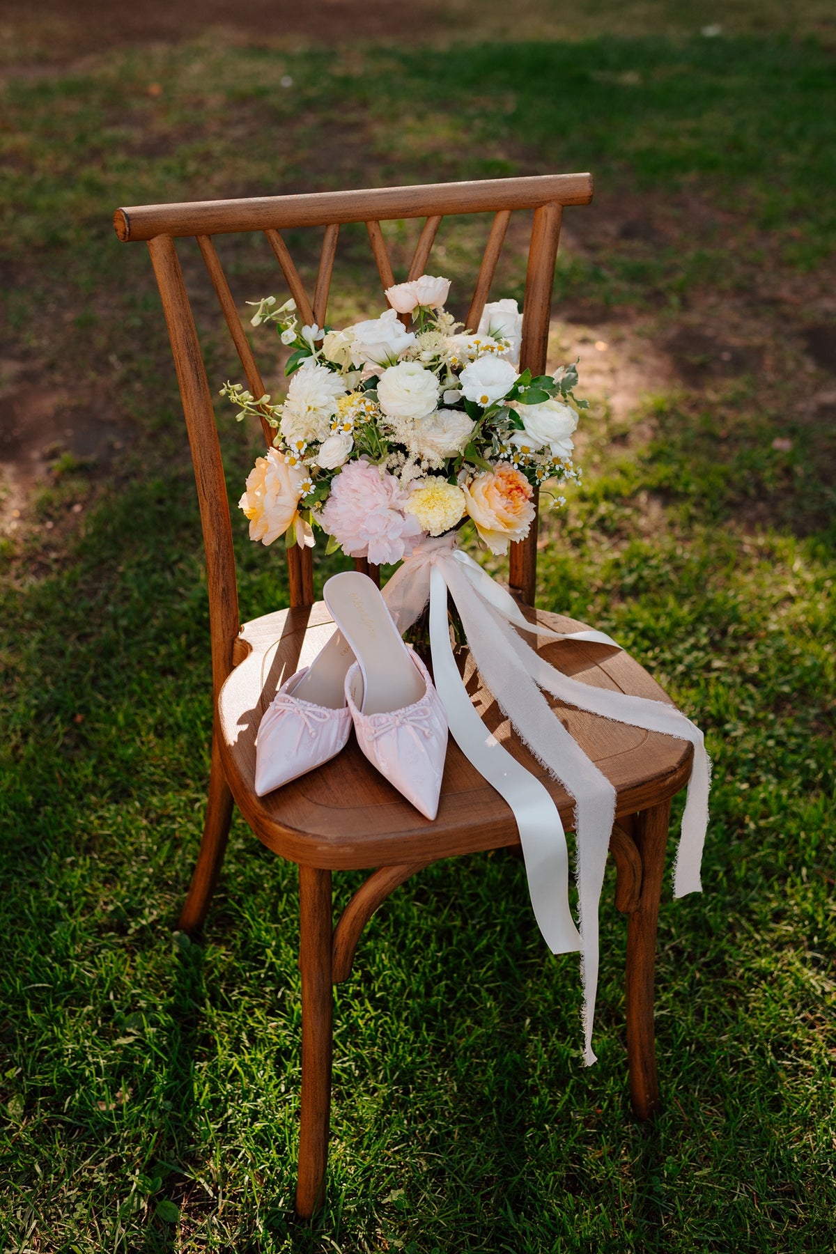 Wooden ceremony chair with peony bridal bouquet and light pink shoes at Green Gables.