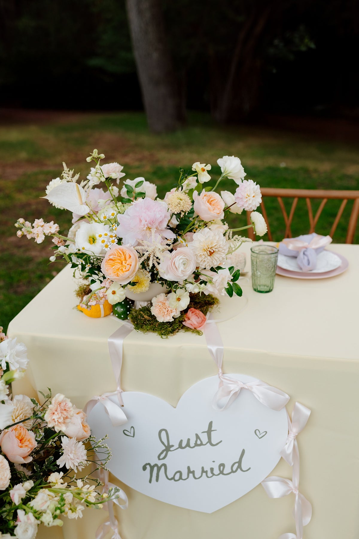Sweetheart table with pastel wedding flowers and 'Just Married' sign.